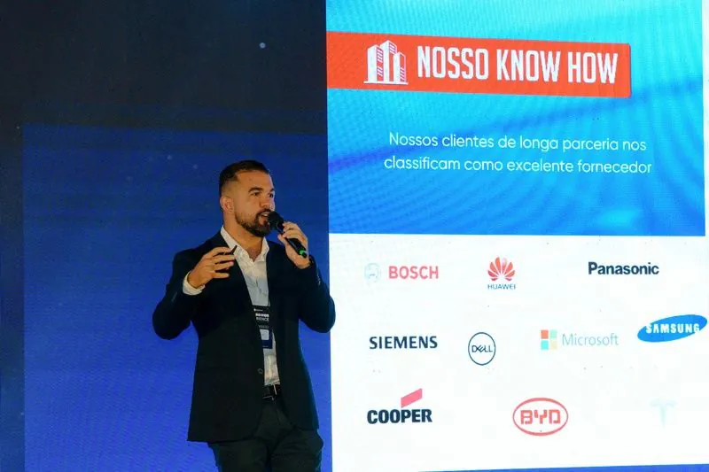 Apresentação da DMEGC Solar no palco, diante do slide “Nosso know how” com os clientes da marca